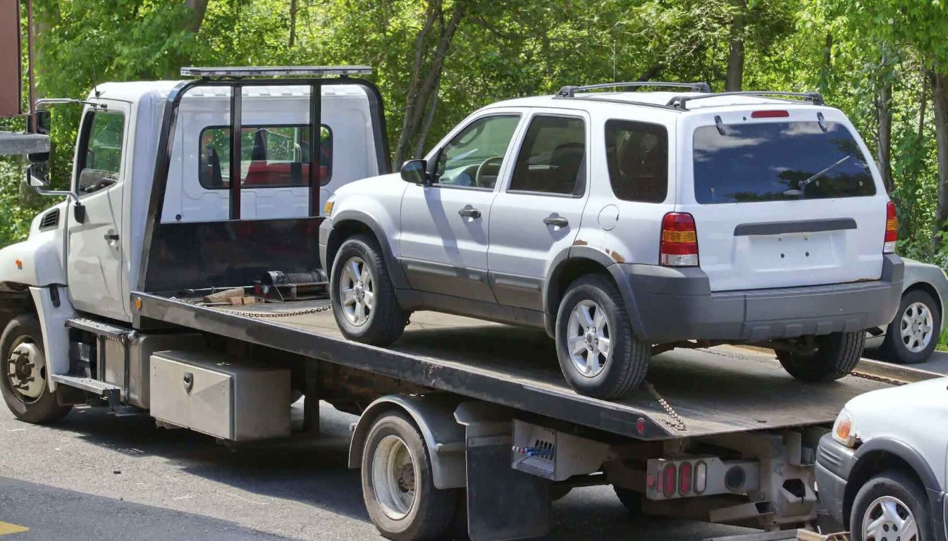 Emergency towing truck loading a white SUV onto a flatbed in Amityville, NY