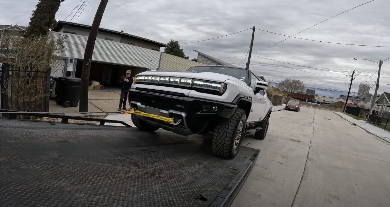 White GMC Hummer EV being loaded onto a flatbed truck for long distance towing